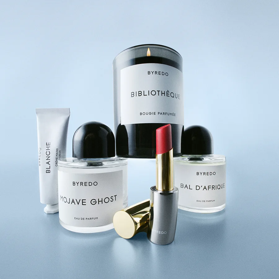Көгілдір фондағы Byredo шамы, хош иістері, ерін далабы және кремі