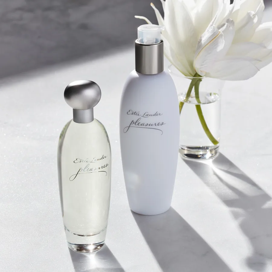 Мәрмәрдегі ақ лалагүлмен бірге Estée Lauder Pleasures құтысы мен лосьоны